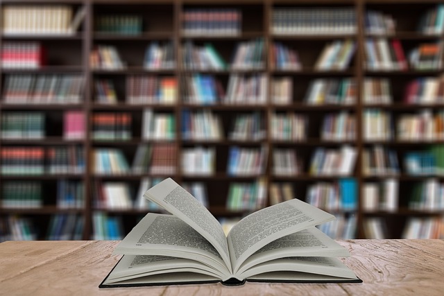 Close-up of open book on a table with blurred bookcases in the background