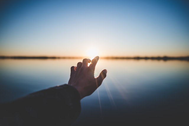 In overcoming inner conflict, your character gets the happy ending they deserve. Close-up picture of a hand reaching toward the rising sun in the background.