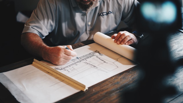 Creating story structure in the early drafting stages gets your writing off to a solid start. When man using pencil to sketch out architectural blueprint design.