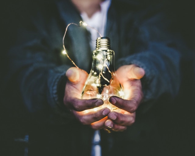 With a year-end review, ideas appear on how to make the following year even more productive. Man holding a lightbulb with shining filament.