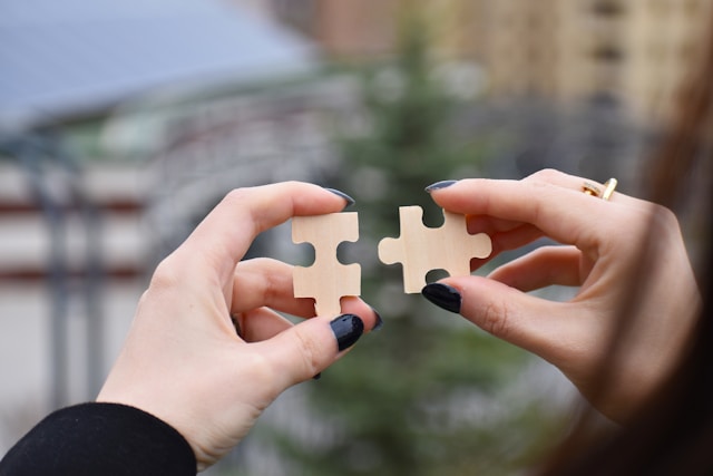 Putting a journey together is like finding the right pieces to your creative puzzle. Closeup of a person's hands holding two fitting puzzle pieces close together.